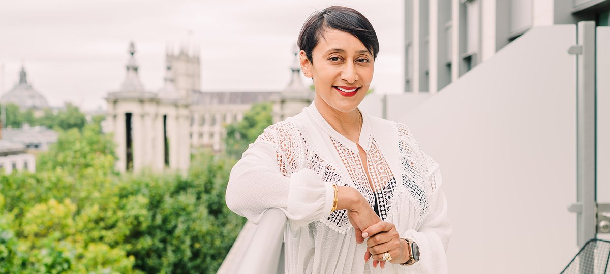 A women stands on a balcony and smiling at the camera