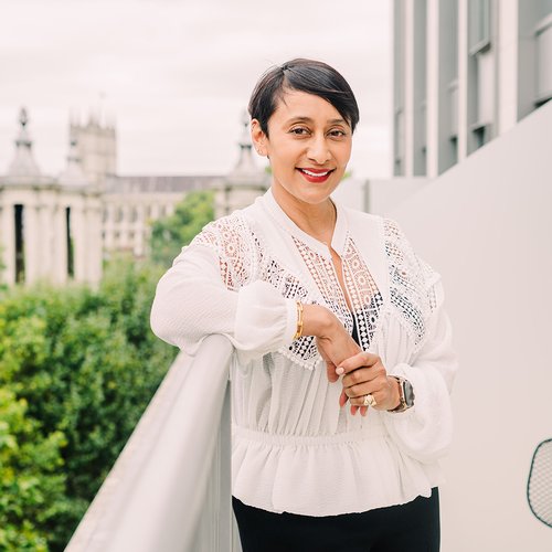 A women stands on a balcony and smiling at the camera
