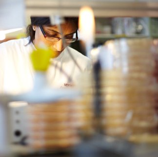 Scientist in a lab, wearing a lab coat, with a Bunsen burner