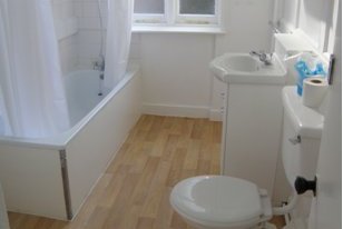 View of bathroom inside staff accommodations showing tub and shower, commode, and sink with window