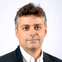 A man with short brown and grey hair smiling