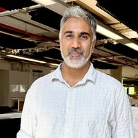 A man with grey hair and beard wearing a white shirt