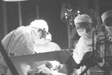 Black and white photo of surgical theatre with staff operating on a patient who is on heart lung bypass