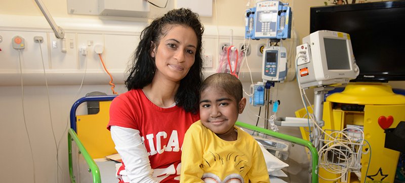 Photo of patient, Keano, sitting with his mum on a hospital bed