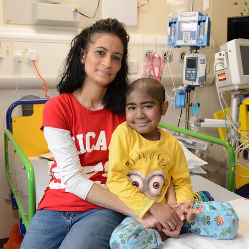 Photo of patient, Keano, sitting with his mum on a hospital bed