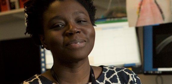 A Black woman smiles at the camera