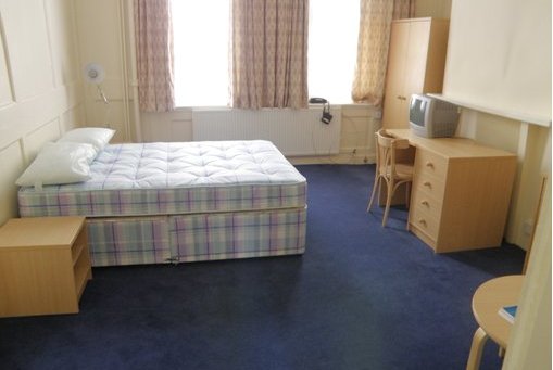 View of the bedroom in the staff quarters with double bed, small bedside table, desk and chair, and double wardrobe.