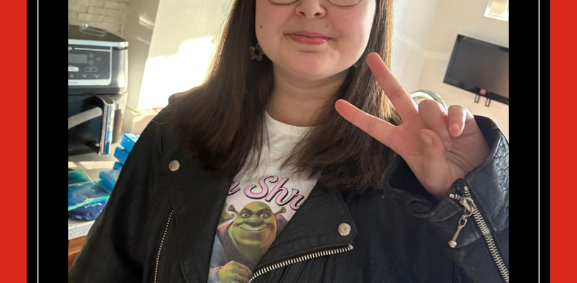 A red and black framed picture of a young woman smiling at the camera holding up two fingers in the 'peace' sign