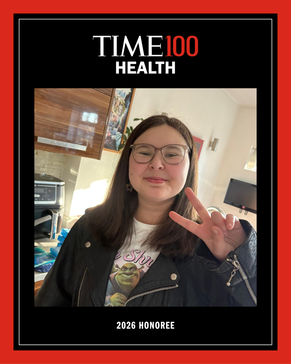 A red and black framed picture of a young woman smiling at the camera holding up two fingers in the 'peace' sign