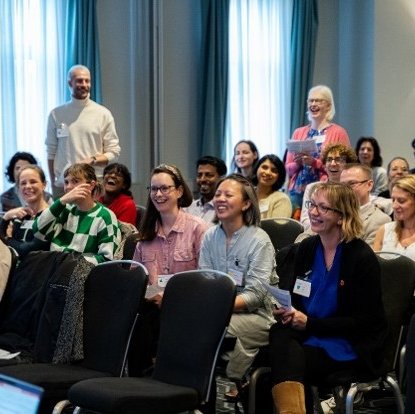 A large group of happy people line up posing for a photograph