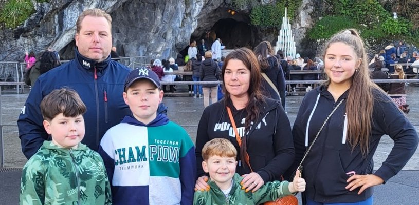A boy stood with his mum, dad, two brothers and sisters