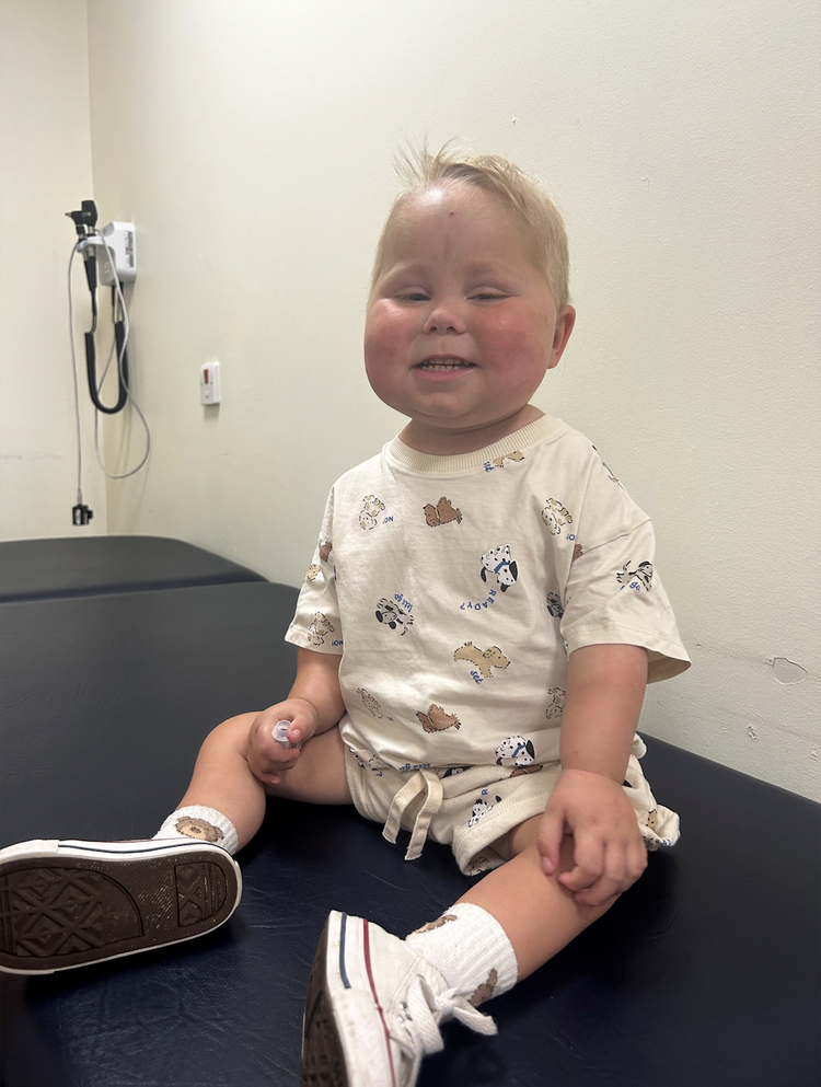 Asher wearing shorts and t-shirt sat on the hospital blue bed