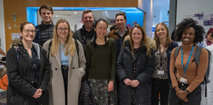 A group of people stand posed for the camera, smiling broadly.