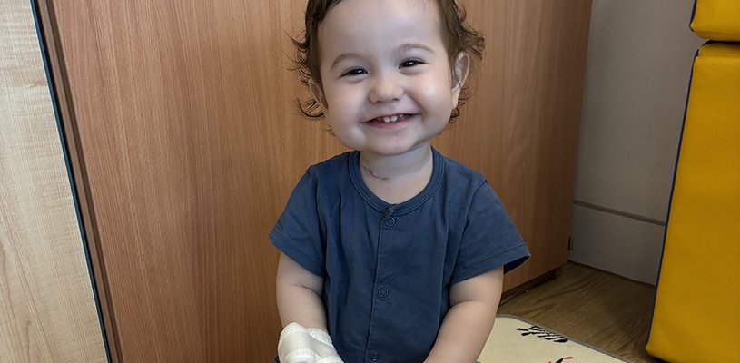 A young boy smiles broadly at the camera
