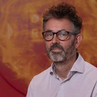 Professor Andrew Taylor, Director of Innovation, wearing shirt and glasses in front of orange DRIVE sign