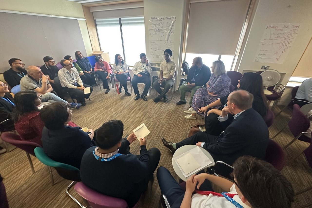 A young person speaking to a big circle of health care professionals