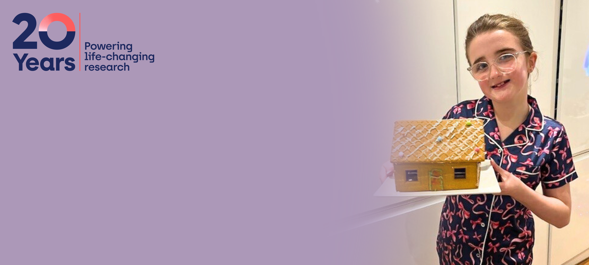 Young girl holds up gingerbread house