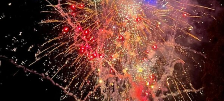 a black background with pink, red, orange and green bright lights exploding in all directions