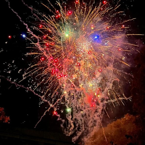 a black background with pink, red, orange and green bright lights exploding in all directions