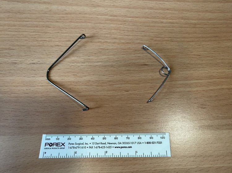 Two springs against a brown table measured against a POREX white ruler