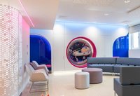 A room with a long blue sofa and pink lights on the wall. There is an illustration of the planets and solar system on the wall.