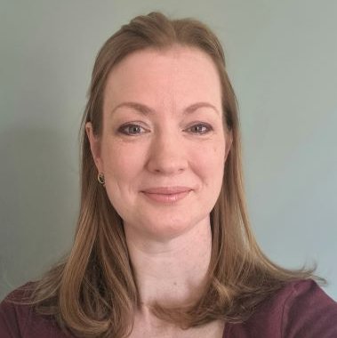 A woman with short brown hair is smiling.