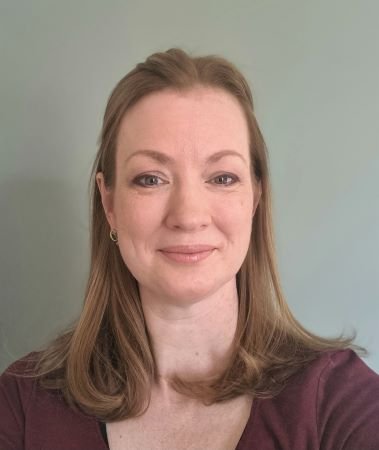 A woman with short brown hair is smiling.