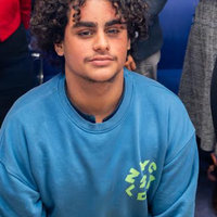 A man with curly dark hair and a blue jumper