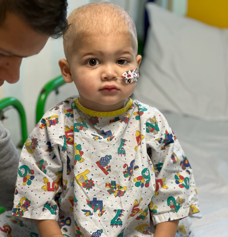 Jacob sitting on a hospital bed wearing a patterned hospital gown
