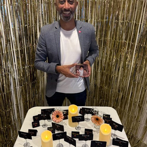 A man smiling, holding a photo of three children