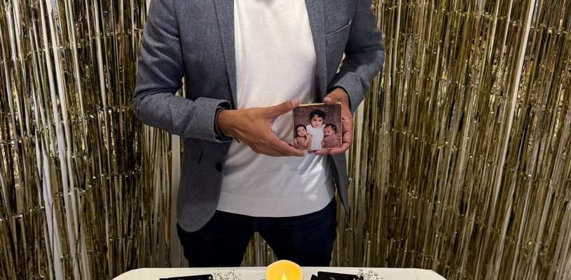 A man smiling, holding a photo of three children