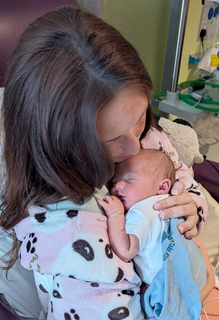 A woman with brown hair holding a baby