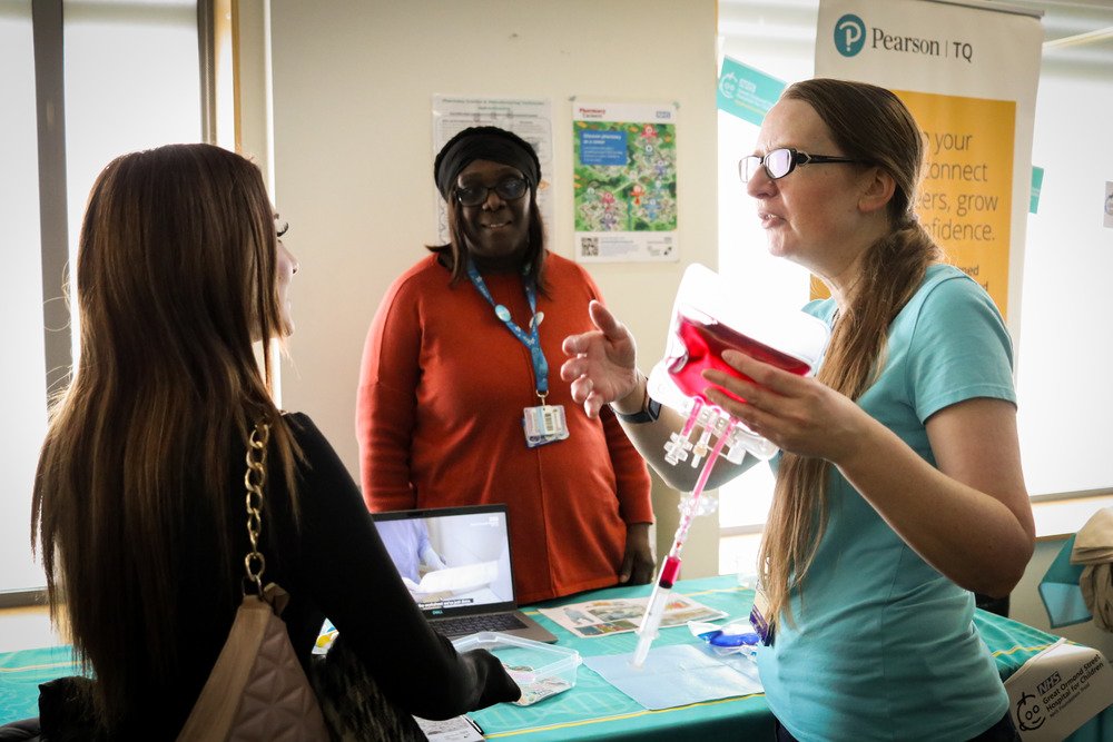 A clinician is showing a student a transfusion bag of blood.