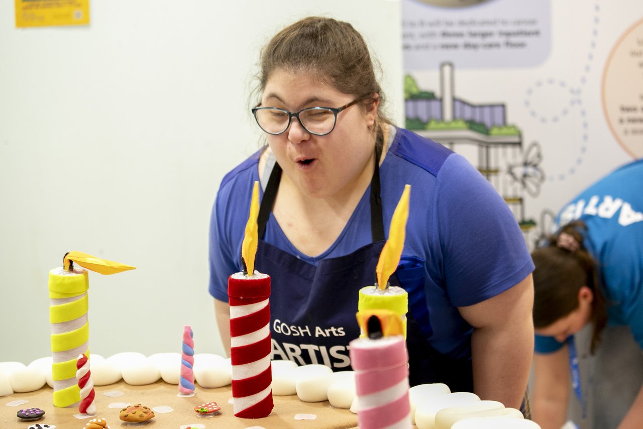 A young women is blowing out candles on a giant cake