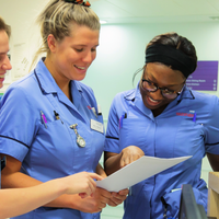 Three nurses are looking at a document together they are all smiling