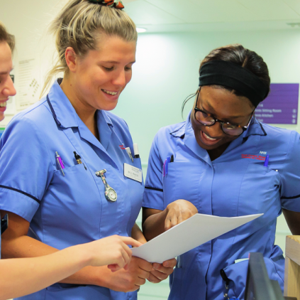 Three nurses are looking at a document together they are all smiling