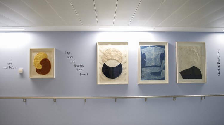 A corridor in a hospital with four abstract artworks on the wall