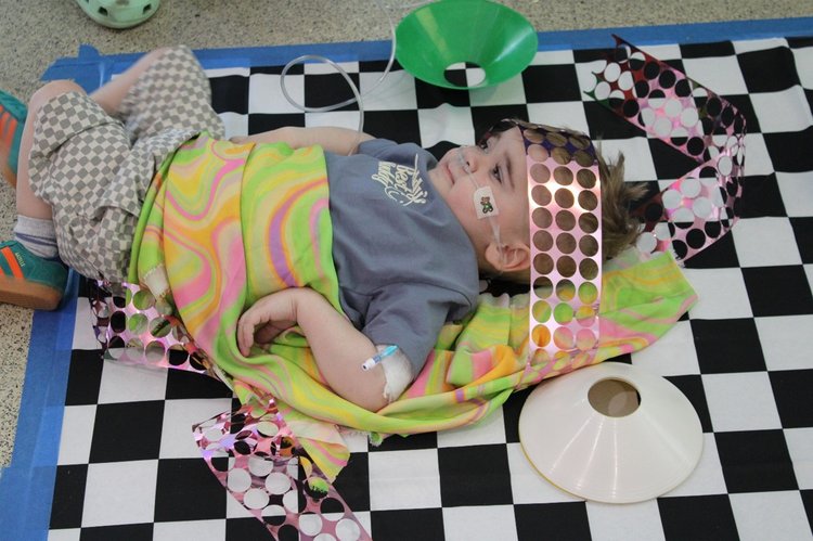 A child laying on a play mat with a blanket over them