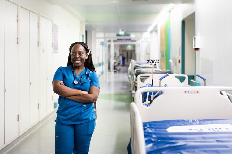 A woman wearing blue scrubs standing in a hospital corridor