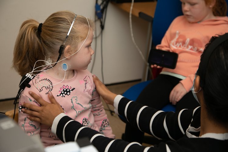 A child sat in a chair with wires attached to her head.