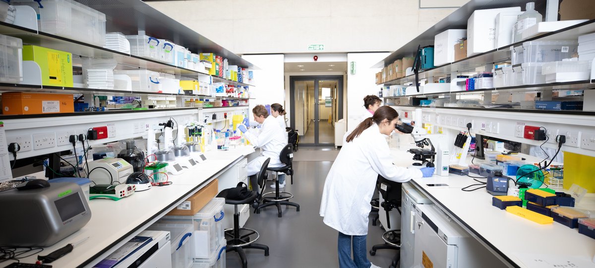 Four people wearing lab coats using lab equipment