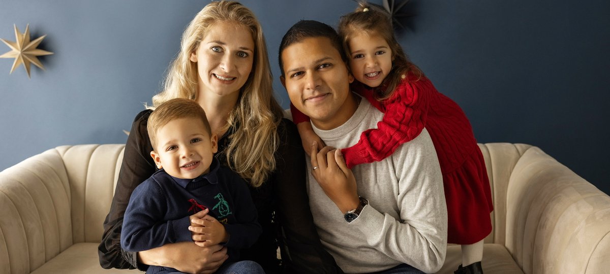 Jacob sitting on sofa with his mum, dad and sister, in front of a navy blue wall