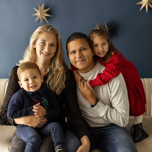 Jacob sitting on sofa with his mum, dad and sister, in front of a navy blue wall