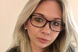 A blonde woman with glasses looks out at the camera