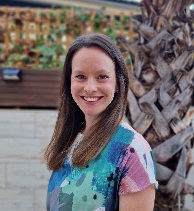 A woman with long brown hair smiles at the camera
