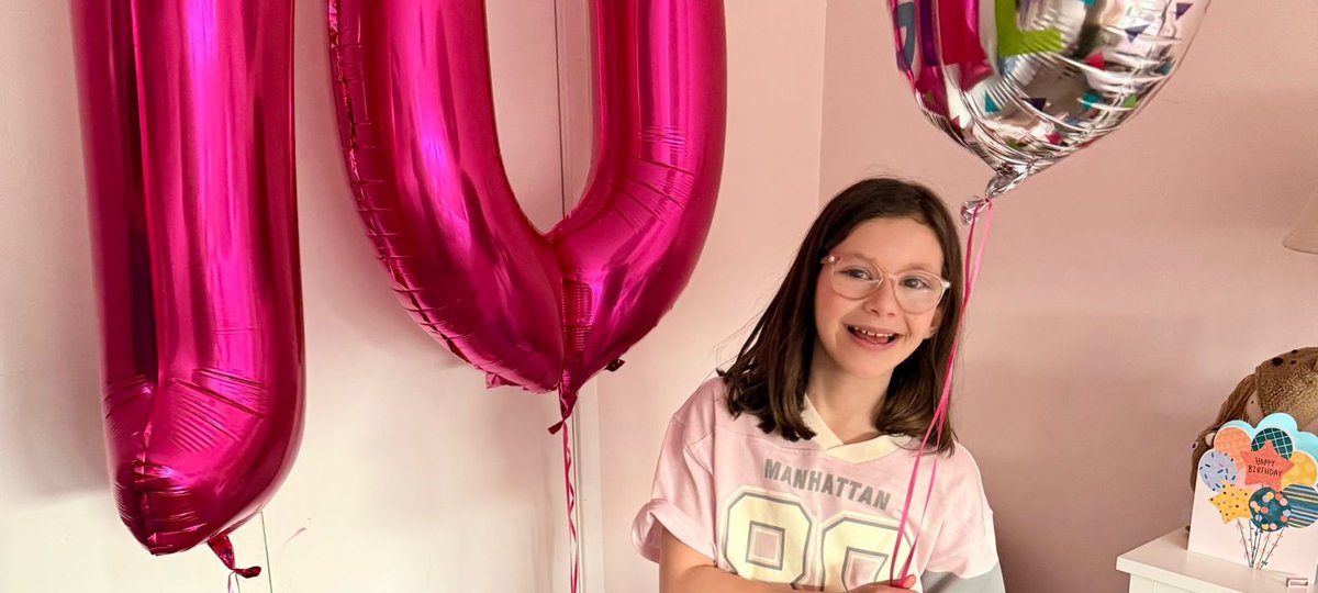 Patient wearing jeans and a t-shirt holding a birthday balloon and 10 balloon