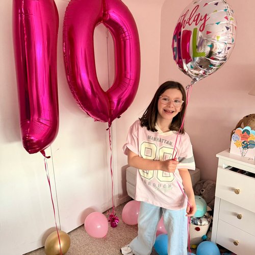 Patient wearing jeans and a t-shirt holding a birthday balloon and 10 balloon