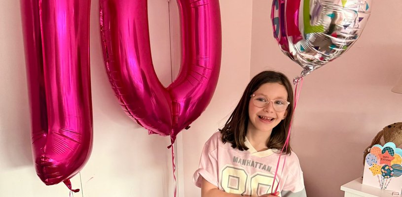 Patient wearing jeans and a t-shirt holding a birthday balloon and 10 balloon