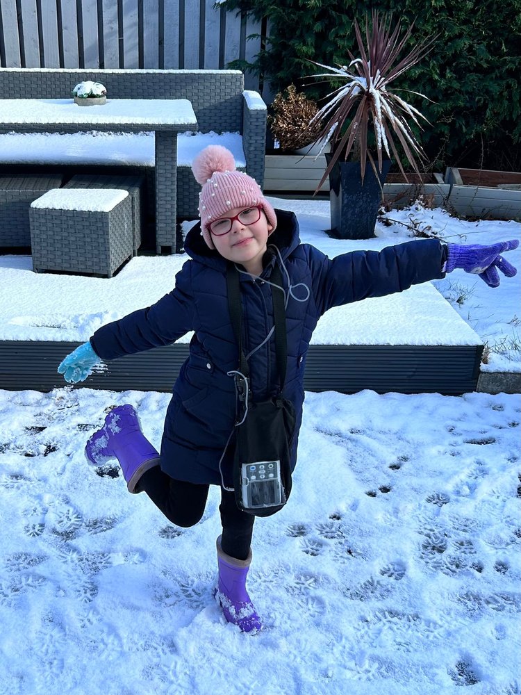 Patient standing in the snow in a coat and wellies with Blina treatment pump