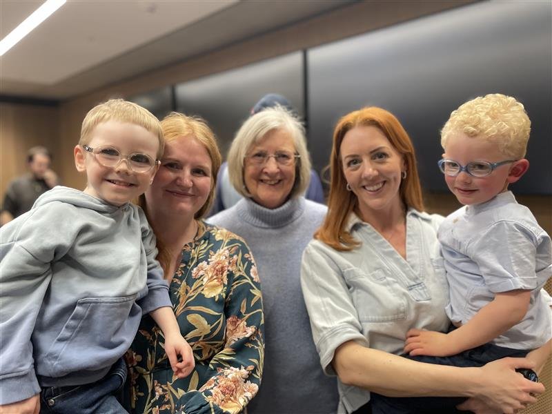 Three GOSH family members holding two young GOSH patients, everyone is smiling.